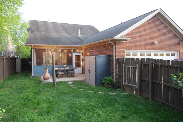 rear view of property with roof with shingles, brick siding, a fenced backyard, a patio area, and a lawn
