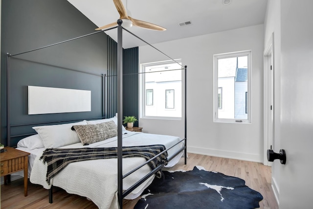 bedroom with baseboards, ceiling fan, wood finished floors, and visible vents
