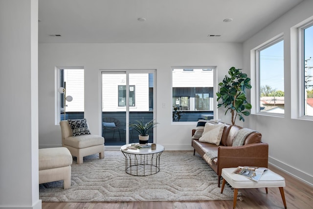 living room with baseboards, visible vents, and wood finished floors