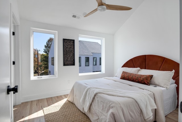 bedroom with vaulted ceiling, a ceiling fan, wood finished floors, and visible vents