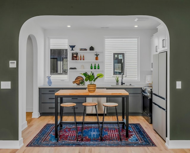 kitchen with a sink, freestanding refrigerator, butcher block counters, and stainless steel electric stove