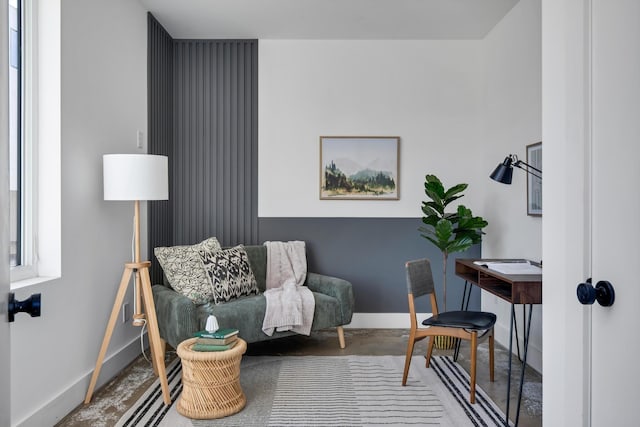 living area with baseboards and concrete flooring