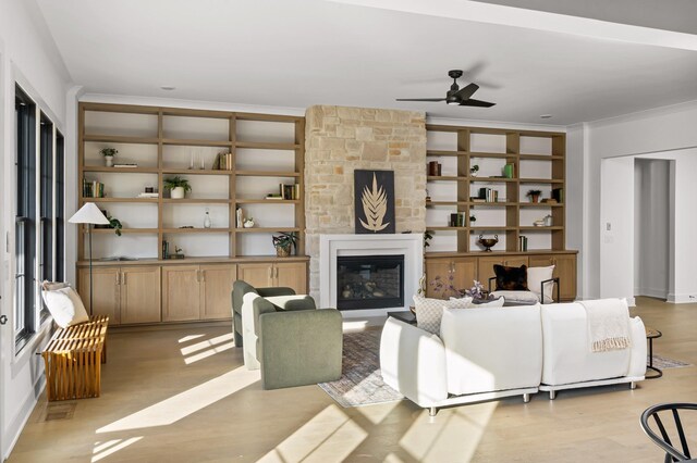 living room featuring ceiling fan, light wood-style flooring, ornamental molding, and built in shelves