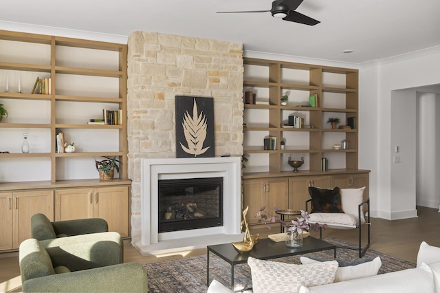 living area with baseboards, ceiling fan, wood finished floors, and a fireplace