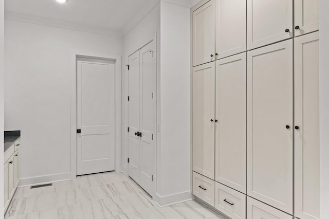 mudroom featuring baseboards, visible vents, ornamental molding, and marble finish floor