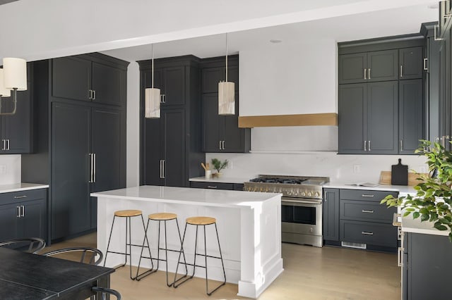kitchen with stainless steel stove, light countertops, decorative light fixtures, and a breakfast bar