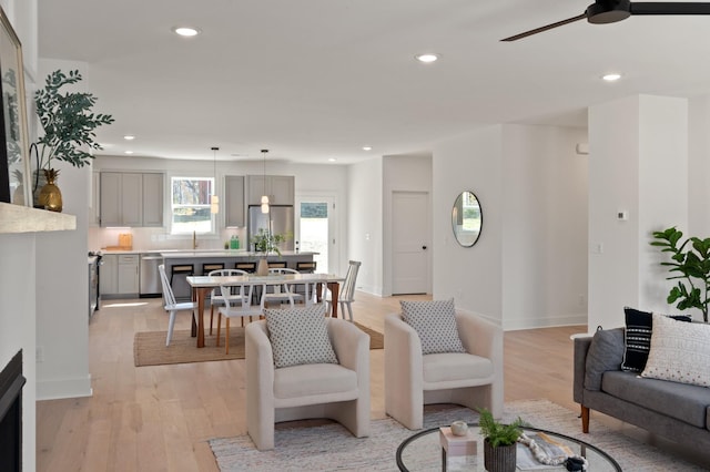 living area featuring baseboards, a ceiling fan, recessed lighting, and light wood-style flooring