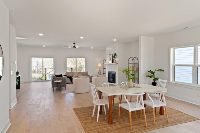 dining area with ceiling fan, baseboards, light wood finished floors, a glass covered fireplace, and recessed lighting