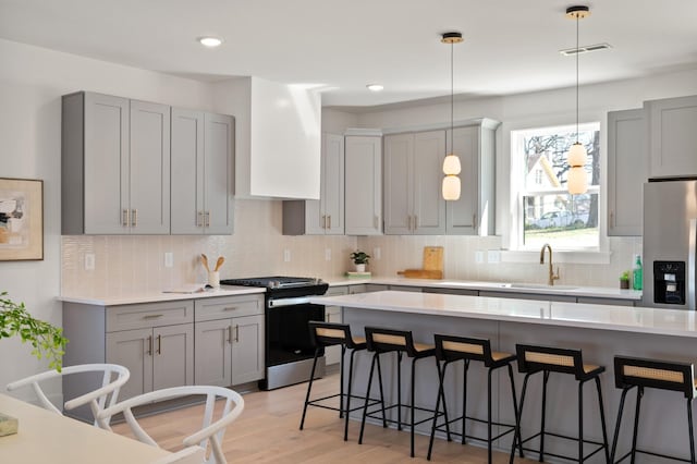 kitchen with gray cabinetry, appliances with stainless steel finishes, and a breakfast bar