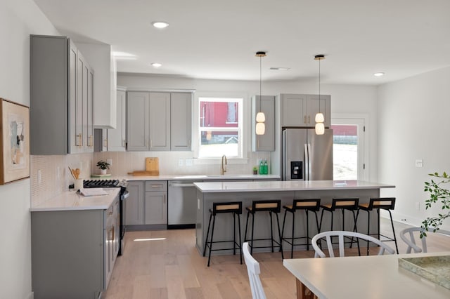 kitchen with stainless steel appliances, gray cabinetry, decorative backsplash, and a kitchen bar