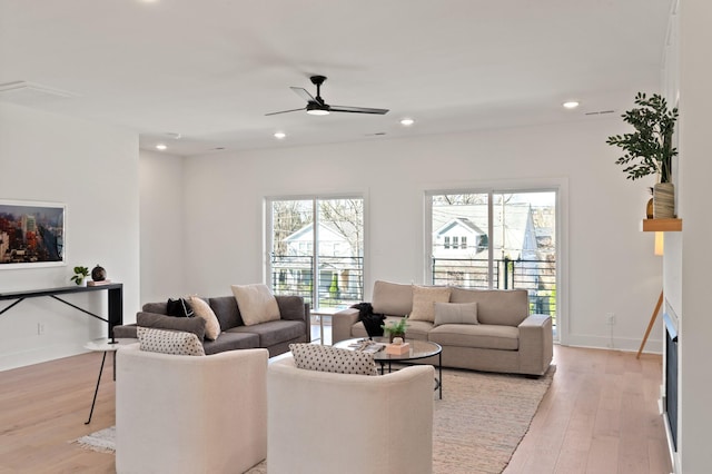 living area with a ceiling fan, plenty of natural light, and light wood-type flooring