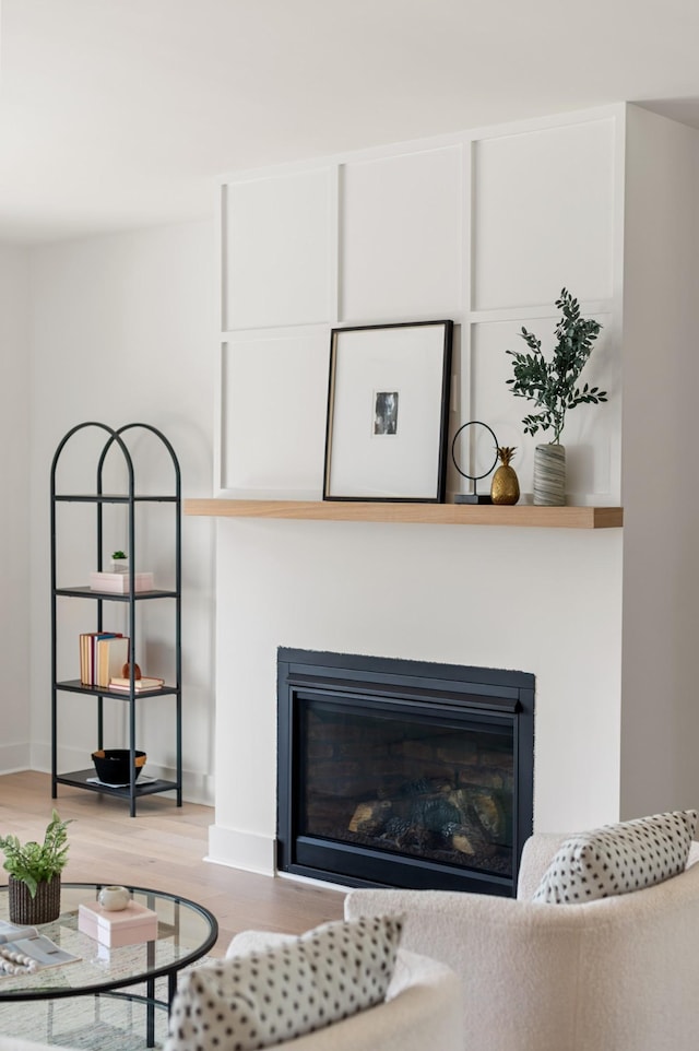 room details featuring a glass covered fireplace, baseboards, and wood finished floors