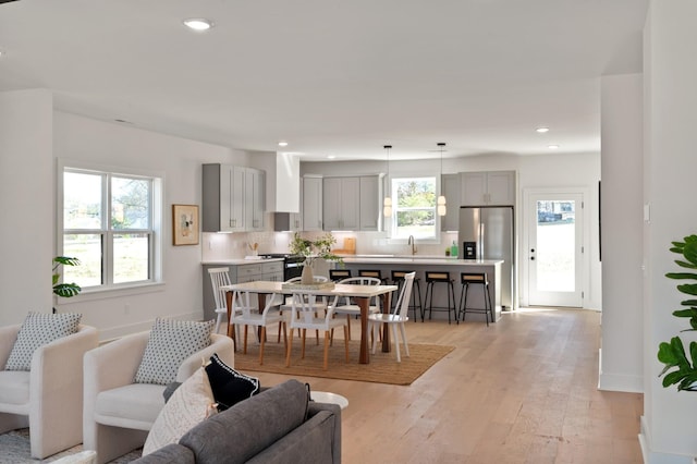 dining room with light wood-type flooring, recessed lighting, and baseboards