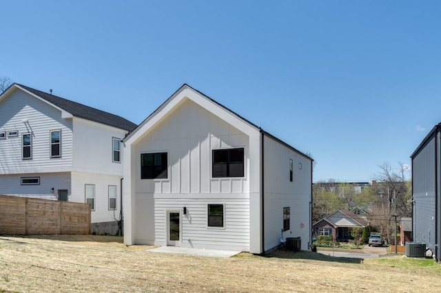 rear view of house with board and batten siding, fence, and cooling unit