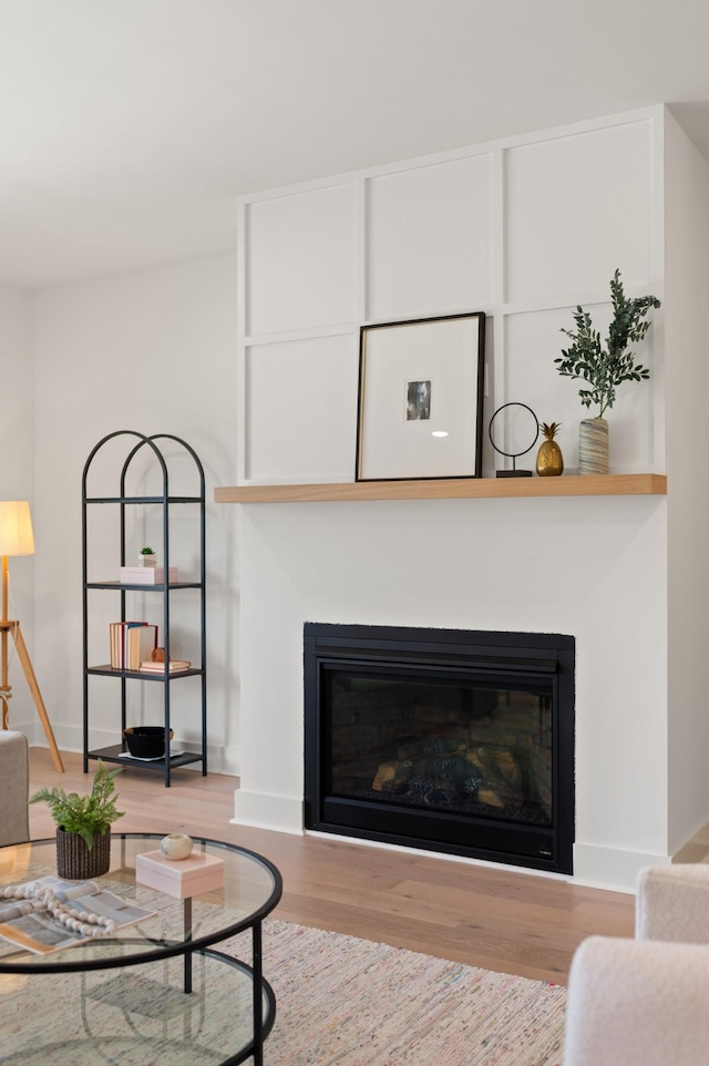 living room featuring a glass covered fireplace, baseboards, and wood finished floors