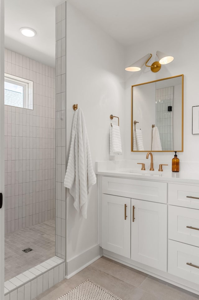 bathroom with vanity, baseboards, tile patterned floors, and tiled shower