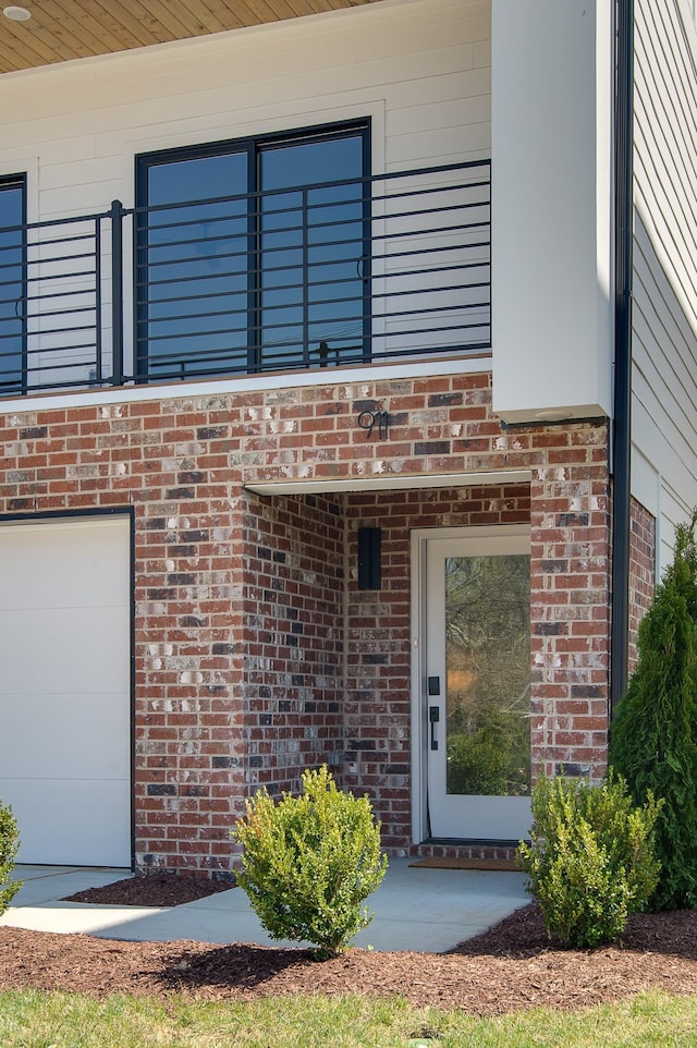 property entrance with a garage and brick siding