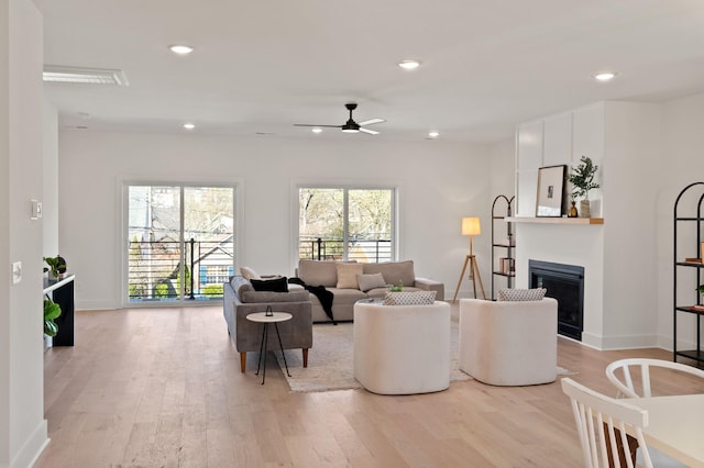living room featuring light wood-type flooring, recessed lighting, ceiling fan, and a fireplace