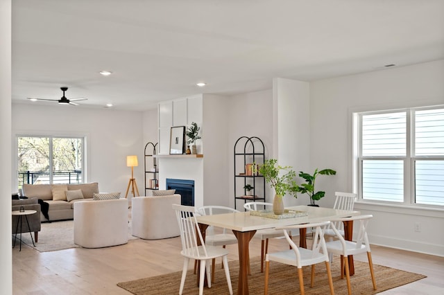 dining area featuring ceiling fan, a fireplace, light wood-style flooring, and a wealth of natural light