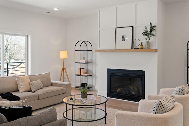 living area featuring recessed lighting, a glass covered fireplace, and wood finished floors