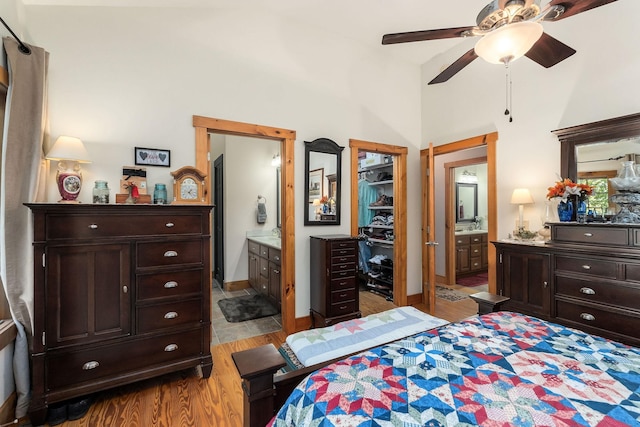 bedroom with wood finished floors, a towering ceiling, ensuite bath, and a spacious closet