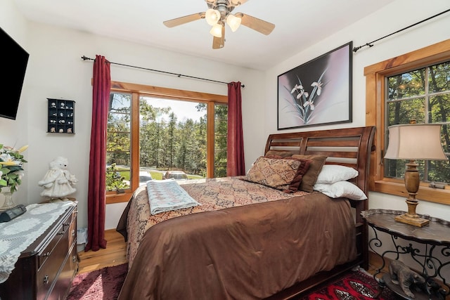 bedroom featuring ceiling fan, multiple windows, and wood finished floors