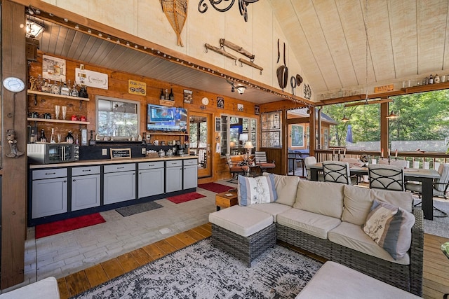 living area featuring wooden walls, high vaulted ceiling, wooden ceiling, and hardwood / wood-style floors