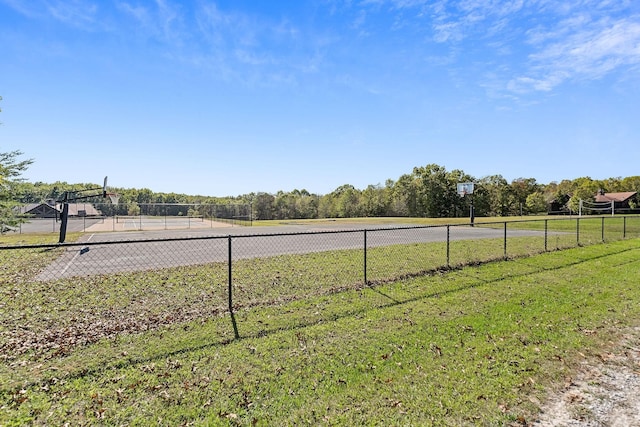 view of yard with fence and a tennis court