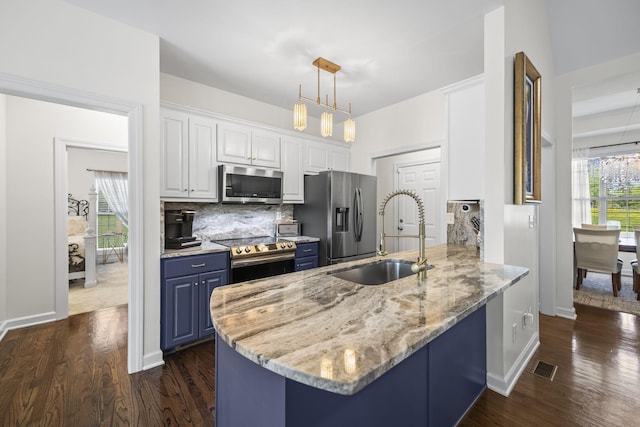 kitchen featuring white cabinets, a sink, blue cabinetry, stainless steel appliances, and a peninsula
