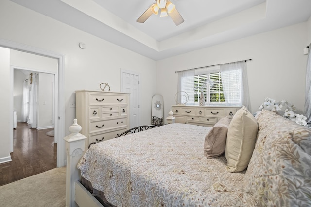 carpeted bedroom featuring ceiling fan and a tray ceiling