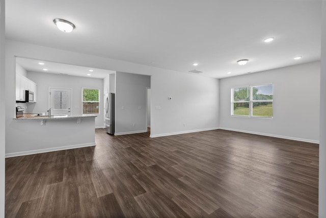 3021 Posada Ct, Spring Hill, TN 37174 - unfurnished living room featuring dark wood-type flooring, recessed lighting, baseboards, and a sink
