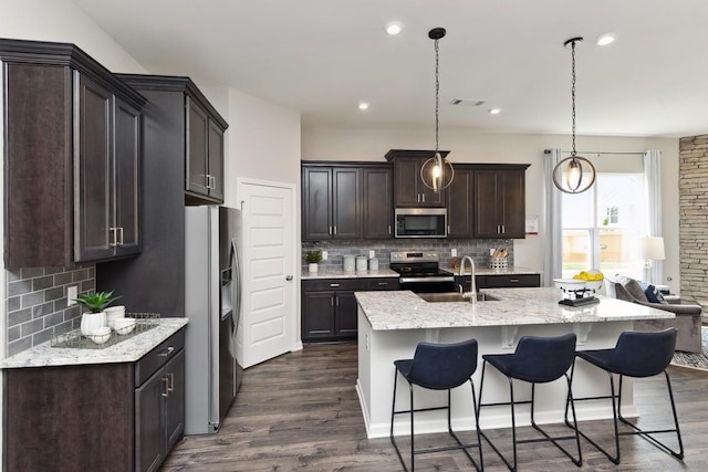 kitchen with a sink, appliances with stainless steel finishes, backsplash, and a breakfast bar