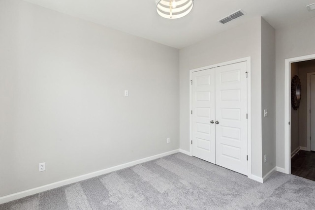 unfurnished bedroom with baseboards, carpet, a closet, and visible vents