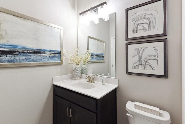 half bath featuring vanity and toilet