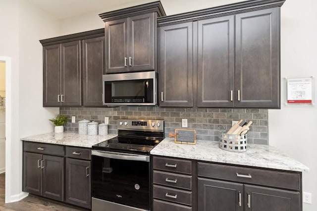kitchen featuring light stone counters, appliances with stainless steel finishes, dark brown cabinets, and tasteful backsplash