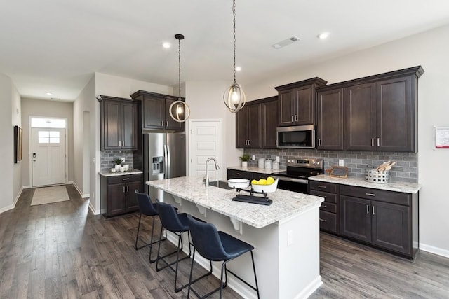 kitchen with visible vents, decorative backsplash, dark wood-style flooring, dark brown cabinetry, and stainless steel appliances
