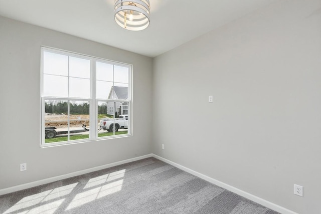 spare room featuring an inviting chandelier, baseboards, and carpet