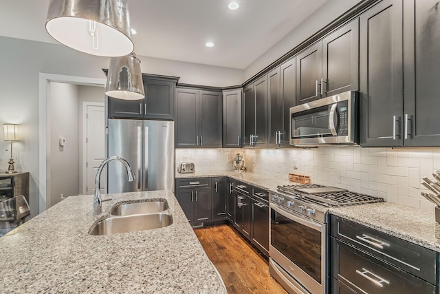 6328B Columbia Ave, Nashville, TN 37209 - kitchen featuring appliances with stainless steel finishes, light stone counters, a sink, dark wood finished floors, and decorative backsplash