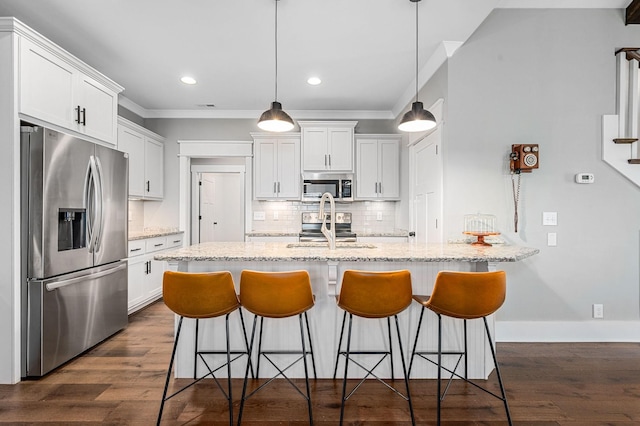 kitchen featuring white cabinetry, appliances with stainless steel finishes, ornamental molding, and a kitchen bar