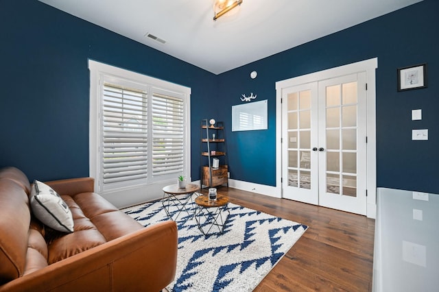 living area with baseboards, visible vents, french doors, and wood finished floors