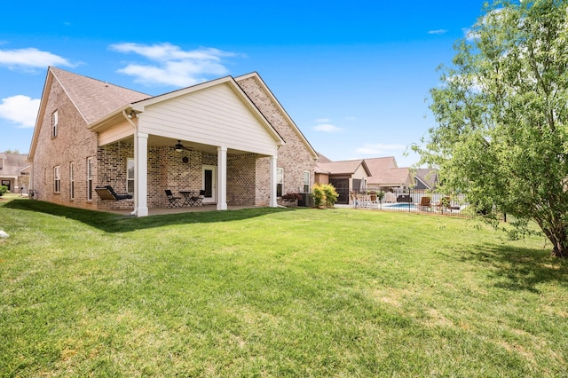 rear view of house featuring fence, brick siding, a patio area, a lawn, and a ceiling fan