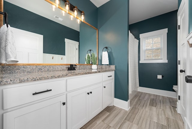 full bath featuring toilet, baseboards, visible vents, and vanity