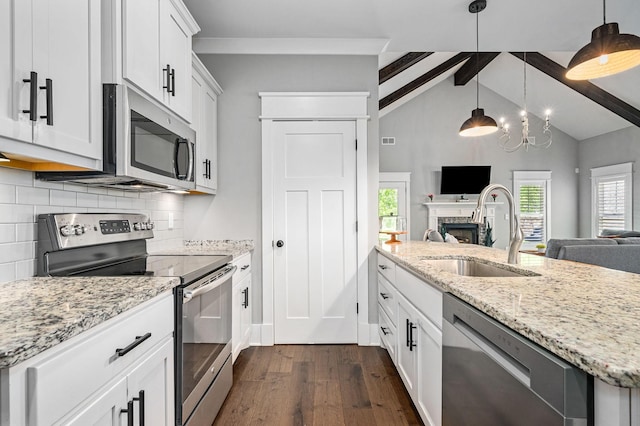 kitchen with appliances with stainless steel finishes, a sink, open floor plan, decorative backsplash, and dark wood-style floors