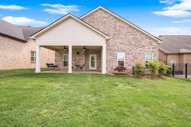 rear view of property featuring fence, brick siding, a ceiling fan, a patio area, and a lawn