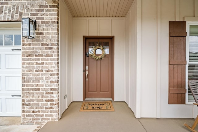doorway to property with board and batten siding and brick siding