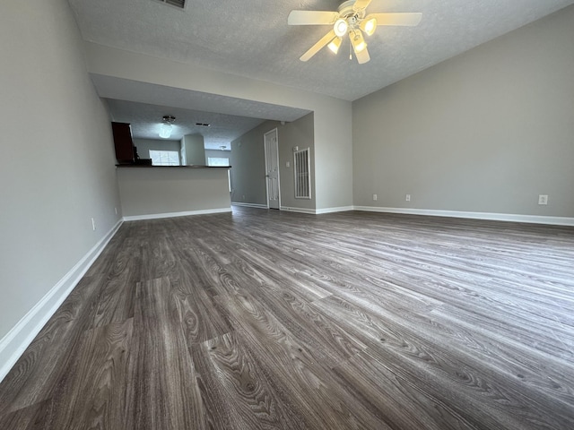 unfurnished living room featuring baseboards, a textured ceiling, dark wood finished floors, and ceiling fan