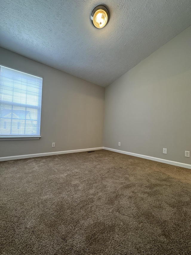 carpeted spare room featuring baseboards and a textured ceiling