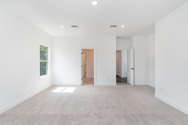 unfurnished bedroom with baseboards, visible vents, recessed lighting, and light colored carpet