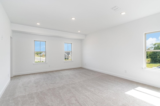 spare room with light colored carpet, recessed lighting, plenty of natural light, and visible vents