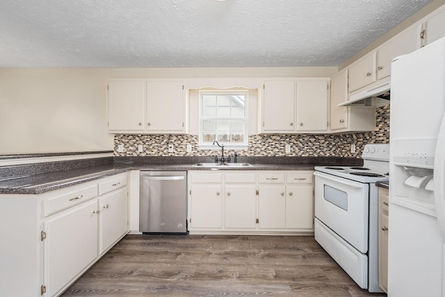 kitchen featuring dark wood-style flooring, a textured ceiling, dark countertops, a sink, and white appliances